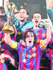 Barcelona's captain Carlos Puyol holds up the trophy, as he and fellow team members react after winning the Club World Cup final against Estudiantes in Abu Dhabi on Saturday, 2009. Barcelona defeated Estudiantes 2-1.