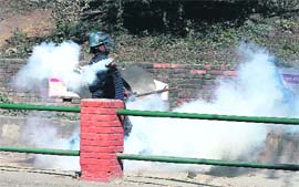 A policeman throws back a teargas shell at demonstrators in Kathmandu on Sunday