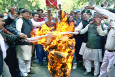 BJP workers burn effigy and shout anti-UPAslogans during their protest against the Rangnath Mishra Committee report at Parliament Street in New Delhi on Monday.