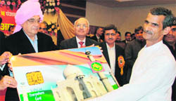 Chief Minister Bhupinder Singh Hooda gives a biometric card to a farmer in Rohtak on Monday.