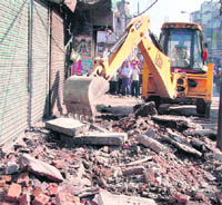 A JCB machine razes structures at Field Ganj in Ludhiana on Monday.