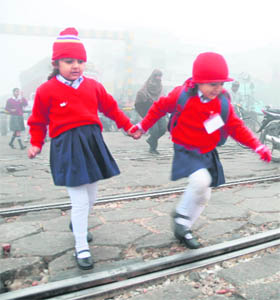 Two little girls head for school on a cold foggy morning in Jalandhar on Monday.