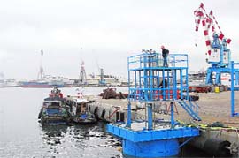 Workers for the Israeli company Seanergy stand on a wave energy system in the port of the northern City of Haifa December 16, 2009. Harnessing the energy of a giant buoy locked underwater may be the key to generating electricity efficiently from waves, Seanergy says