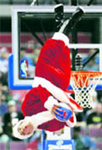 A member of the Detroit Pistons 'Flight Crew' dunk team, in a Santa suit, flips upside down during a time-out in their game against Toronto Raptors in Michigan on Thursday