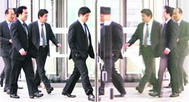 MIRROR IMAGE: Japanese businessmen enter a building in Tokyo on Friday. Japans jobless rate edged up in November, but the availability of jobs rose further from a record low.