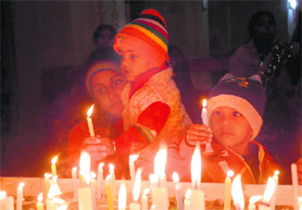 A mother lights a candle with her child at The Church of Ascension in Karnal on Christmas on Friday.
