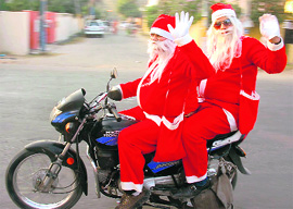Two men dressed as Santa Claus ride a bike on Christmas in Jammu on Friday.