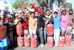 Consumers stage a protest and block traffic on Amrik Singh Road demanding a regular supply of LPG cylinders in Bathinda on Friday.