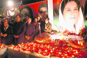 Supporters of Pakistan's slain leader Benazir Bhutto stand beside her portrait after lighting earth lamps at a ceremony to mark the second anniversary of her death in Lahore. Bhutto was assassinated in Rawalpindi on December 27, 2007