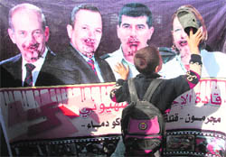 A Palestinian boy holds up a shoe to a banner depicting (from left) Israel's former Prime Minister Ehud Olmert, Defence Minister Ehud Barak, army chief Lieut-Gen Gabi Ashkenazi and opposition party leader Tzipi Livni during a rally in Jabalya in the northern Gaza Strip marking the first anniversary of Israel's three-week offensive in Gaza on Sunday.