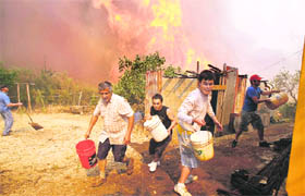 Residents run to refill buckets of water to use in preventing homes from catching in Valparaiso city in Santiago.