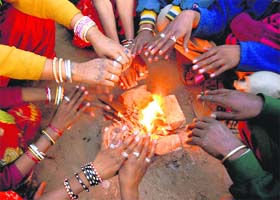 A group of people warm their hands around a fire to beat the chill in Karnal