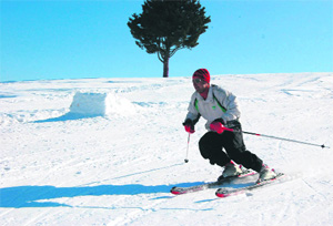 A tourist skies amid bright sunshine on snow-covered slopes of Gulmarg, around 53 km north of Srinagar, on Tuesday.