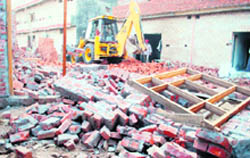 A JCB machine demolishes houses of an illegal colony at Haibowal on Tuesday. 