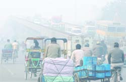 Commuters pass through a road in dense fog in New Delhi