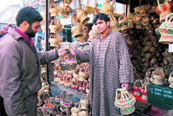 A shopkeeper shows a Kangri, traditional Kashmiri firepot, to a customer in Srinagar on Wednesday. The Kangris are in big demand these days due to harsh cold conditions in the Kashmir valley