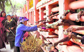 A Buddhist devotee gives alms to beggars at Mahabodhi temple during the 27th Kagyu Monlam for world peace in Bodhgaya on Thursday
