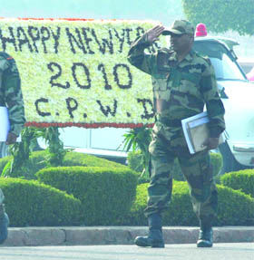 A jawan salutes in front of a New Year greetings board at Vijay Chowk in New Delhi on Friday.