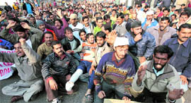 Daily wage employees of the PDD block the Janipur High Court road in Jammu on Friday