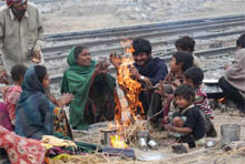 A family gathers around a bonfire to beat the cold;