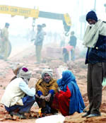 Workers warm themselves with firewood at Rajpath in New Delhi on Saturday.