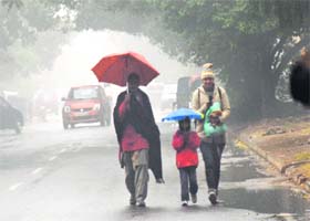 Two women and a child hurry for their destination amid rain and fog