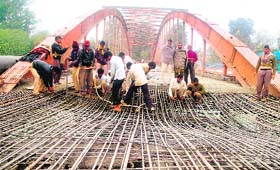 Workers repair a portion of the Damkoti bridge that collapsed hours after it was laid in Haridwar