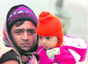  A man with his baby wrapped in woollens in Jammu on Tuesday. 