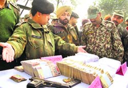 Officials of the BSF with cash and items seized after a smuggler was shot dead