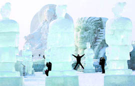 Visitors pose near giant sculptures made from ice and snow before the opening ceremony of the Harbin International Ice and Snow Festival in Harbin in northeastern's China Heilongjiang province on Tuesday