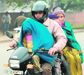 A motorcyclist and his family brave the chill with shawls in Chandigarh on Wednesday.