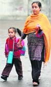 A woman drops her kid at a school after the winter vacation in Jammu