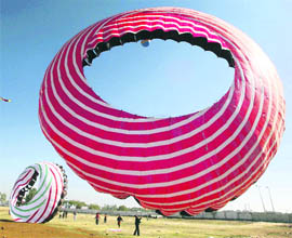 Kite fliers trying to fly a Windsock with a diameter of 50 feet during a practice session ahead of the 20th International Kite Festival in Ahmedabad.