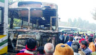 People surround the charred DTC bus at Aruna Asaf Ali Marg in New Delhi on Saturday.