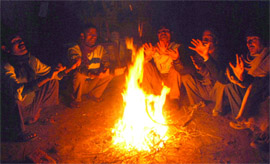 People warm themselves around firewood at ITO on Sunday. 