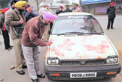 A fingerprint expert examines the blood-smeared car found abandoned at Feroze Gandhi market in Ludhiana on Sunday.