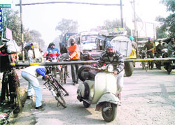 Two-wheeler riders risk their lives by crossing a level crossing closed for the passage of a train at Sahnewal. The persistent closure of the crossing has become a source of nuisance for motorists and residents.