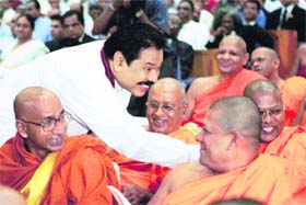 Sri Lankan President Mahinda Rajapaksa greets Buddhist monks as he hands over his election manifesto during its launch in Colombo