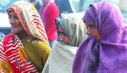 Women cover themselves with shawls at the India Gate in New Delhi on Thursday.