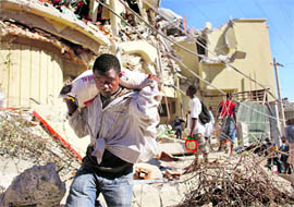 A resident loots food from the destroyed Caribbean supermarket in downtown Port-au-Prince on Thursday