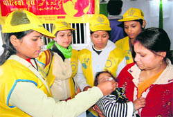 NCC cadets administer polio drops to a child at railway station in Dehradun on Friday