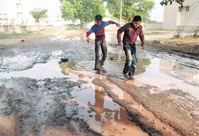 Children have a hard time crossing a potholed stretch of road in Sector 31, Chandigarh