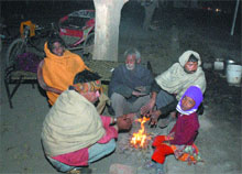A homeless family sits by a bonfire to fight cold near DC office in Jalandhar. 