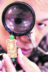 Taiwanese artist Chen Forng-shean poses behind a magnifier with a necklace in Taipei on Sunday. Chen created various tiger figurines and necklaces bearing illustrations of the animal to welcome the upcoming Lunar Year of the Tiger. 