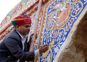 An artist paints a wall as he prepares for the annual craft fair at Surajkund in Faridabad