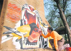 An artist paints a wall for the annual Surajkund Crafts Mela in Faridabad