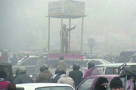 A cop tries to control traffic on a foggy day in Faridabad