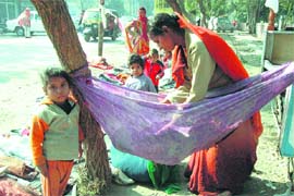 A mother tries to put her infant to sleep in a swing on the Railway Road in Ambala Cantonment