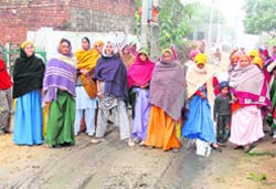 Residents have a tough time walking on a muddy road in Fatehpuri village