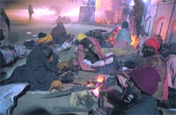 Hermits try to catch some warmth sitting near a bonfire in Gurgaon
